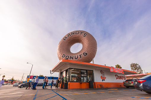 Inglewood, CA - December 12/21/2019: Randy's Donuts Famous Building, located in Inglewood, California, near Los Angeles Airport, designed by Henry J. Goodwin. People waiting in line to buy donuts.