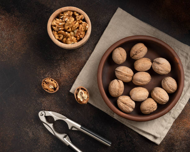 istock unpeeled walnuts, nutcracker and peeled kernels on a brown background. 1222631393