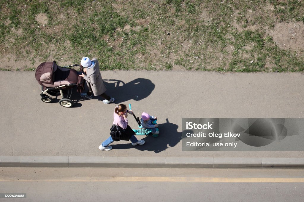 Mujeres con un cochecito de bebé y un niño en una bicicleta de juguete caminando por una calle de la ciudad - Foto de stock de Top libre de derechos
