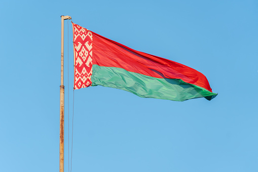 Belarus National Flag Waving on pole against deep blue sky background. High Definition