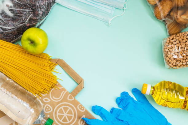 istock Food for quarantine isolation period flat lay on light blue background with copy space. Cooking oil, pasta, water and beans. Crisis food supplies. 1222635602