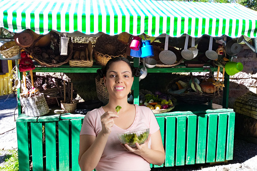 portrait of woman with virtual background eating broccoli in front of the fair stand
