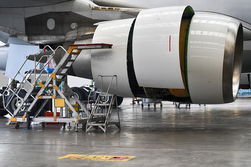 Top view of a white passenger jet plane in the aviation hangar. Airliner under maintenance. Checking mechanical systems for flight operations