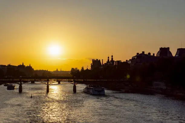 Sunset over Seine river and Pont des arts with palais royal and musee d'orsay in background - Paris, France