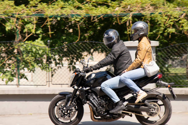 Couple riding on a motorbike a city sidewalk stock photo