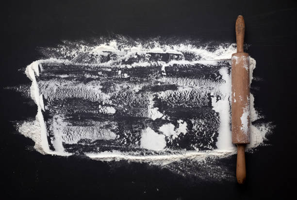 istock white wheat flour scattered on a black table and a wooden rolling pin on a black table 1222642049