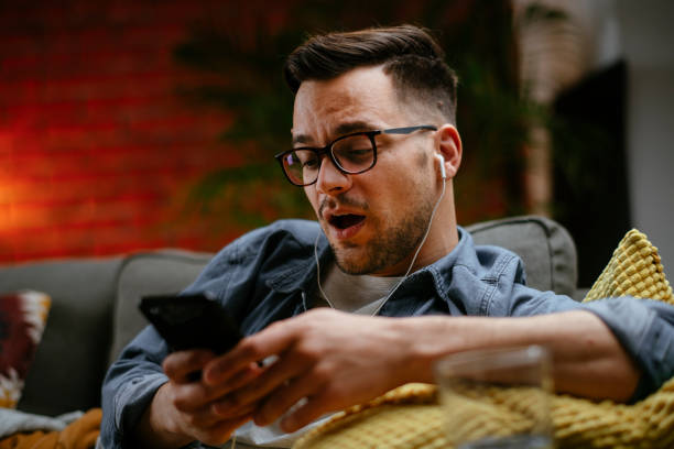 istock Handsome young man relaxing on sofa and looking at his smart phone. 1222642053