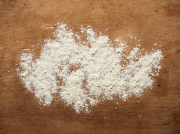 istock white wheat flour scattered on a brown wooden table, top view 1222642223