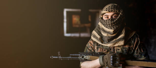 arabischer männlicher soldat in einem kopfschmuck aus dem nationalen keffiyeh mit waffen in den händen. muslimischer mann mit pistolen auf schwarz - jihad stock-fotos und bilder