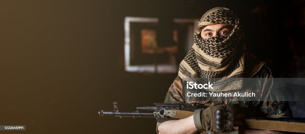 Arab male soldier in a headdress from the national keffiyeh with weapons in his hands. Muslim man with guns on black Arab male soldier in a headdress from the national keffiyeh with weapons in his hands. Muslim man with guns on black. Militant Groups Stock Photo