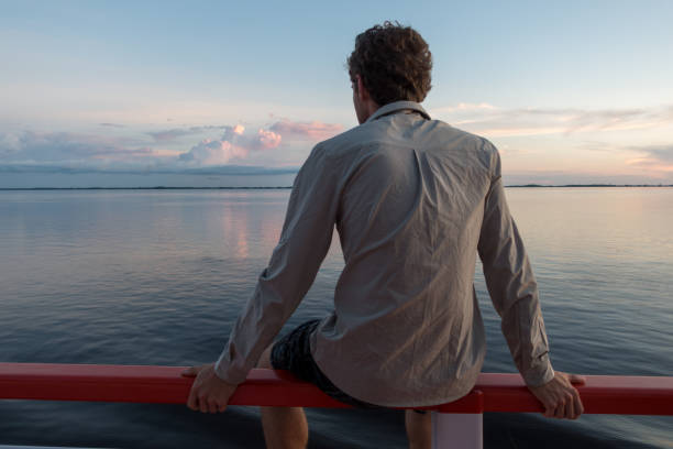 Young man sits on a railing on a boat