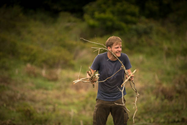 istock Young man carries dead branches out of forest clearing 1222647147