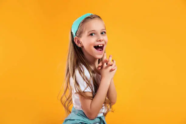 Photo of surprised little child girl in summer clothes on a colored yellow background. Vacation concept