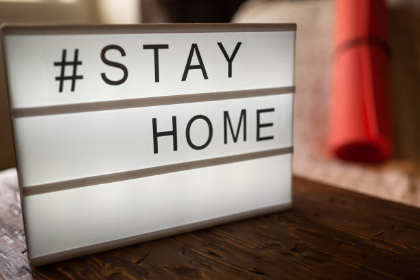 istock Coronavirus Yoga at home sign lightbox with text hashtag STAY HOME glowing in light with exercise mat, cork blocks. COVID-19 banner to promote self isolation staying at home 1222648105