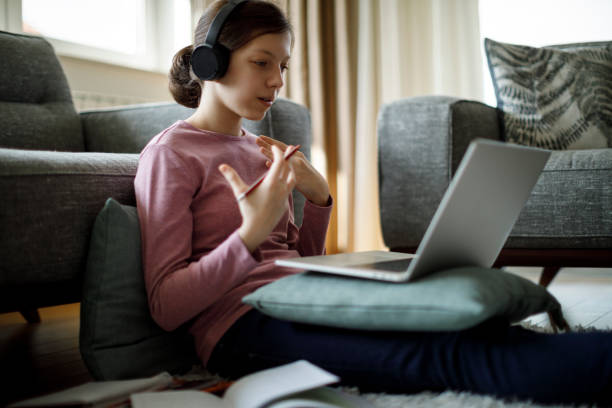 adolescente com fones de ouvido e laptop tendo aula online em casa - high school audio - fotografias e filmes do acervo