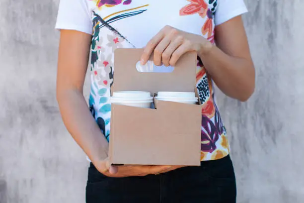 Woman's hands holding a paper cup holder