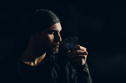 Man smoking a pipe on dark background