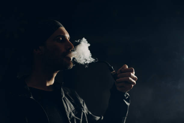 istock Man smoking a pipe on dark background. Profile portrait. 1222651196