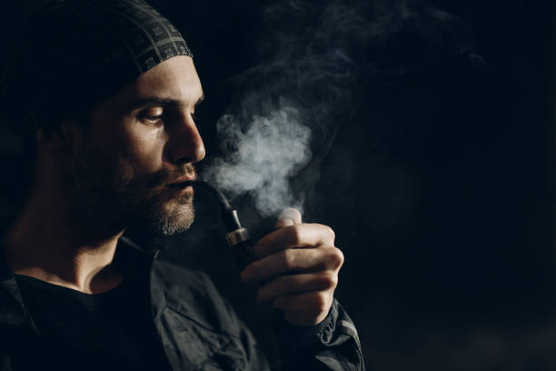 istock Man smoking a pipe on dark background. Profile portrait. 1222651197