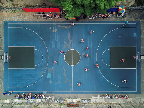 Top view of the basketball court during the game. The players are on the field, spectators on the perimeter. Outdoors