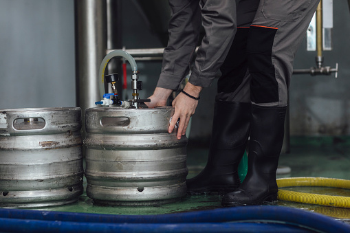 Man in a uniform loading metal kegs with craft beer.