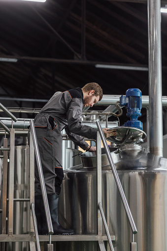 Lager making process: man in a uniform checking a fementation tank.