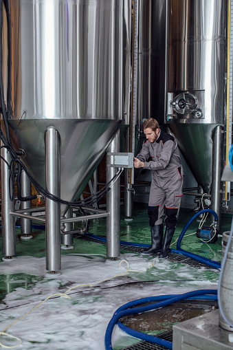 Operator working at a brewery controlling the storage tanks using a tablet computer - industrial concepts
