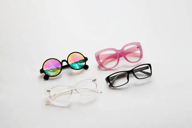 Photo of Different glasses in different colors lie diagonally in the center of a white background