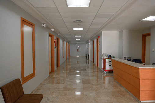 Empty hospital corridor. Yellow walls, many doors.