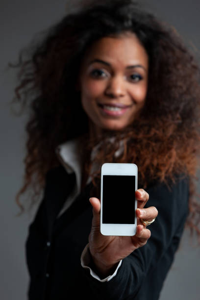 istock Smiling friendly woman holding out a mobile phone 1222652845