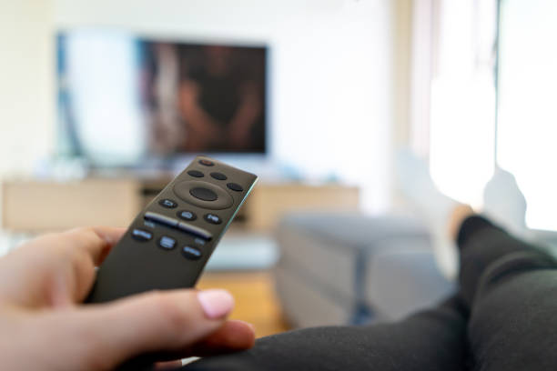 istock Watching TV, hand holding remote controller in front of big television 1222655707