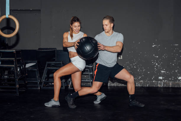 мужчина и женщина спортсмены обучение вместе, проходя mecicine ball - pass the ball стоковые фото и изображения