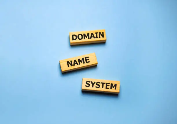 DNS - Domain Name System, acronym technology concept on wooden blocks on blue