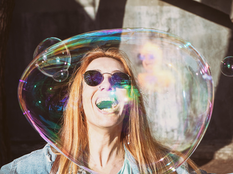 Beautiful girl in sunglasses and big soap bubble near her face