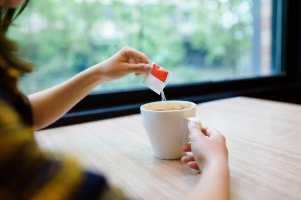 frau gießt zucker in kaffee. - sugar sachet stock-fotos und bilder