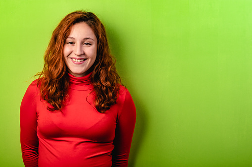 beautiful redhead girl with red shirt and green background. Copy space for text