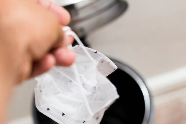 istock subject depositing surgical mask in the garbage container 1222661820