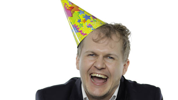 istock Drank sleepy young businessman with hangover in festive cap laughs 1222662700