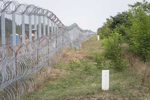 Picture of the wall made of barbed wire erected on the border between Serbia and Hungary, between the villages of Kelebija and Tomba with a focus on a boundary marker materializing the border. It was built during the refugees crisis to stop the refugees from taking the Balkans Route\