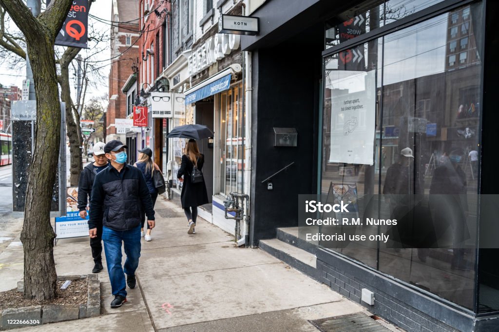 Toronto Locals Wearing Face Masks on the Streets During Coronavirus Pandemic, Ontario, Canada Toronto, Canada - May 02, 2020: Locals on the streets of Downtown Toronto on a rainy day during coronavirus pandemic in Ontario, Canada. Canada Stock Photo
