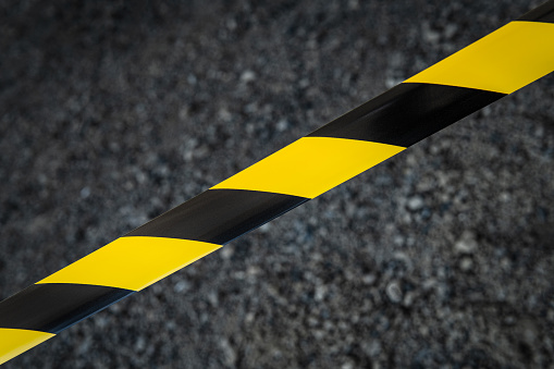 Black and yellow striped tapes on dark background. Restricted area border. Passage is forbidden.