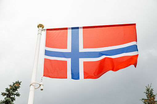 Norwegian flag on a flagstuff in front of the sky