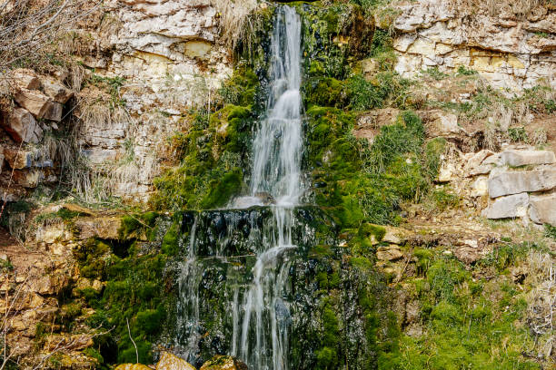 Beautiful mountain waterfall among the stones. A source of water in arid areas. Rocks covered with moss. Motion blur
