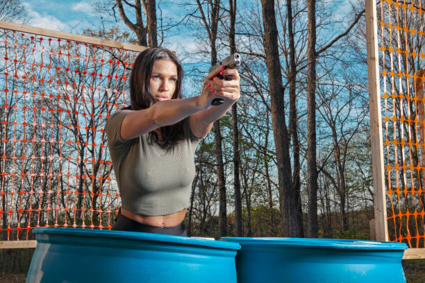 Female in her 30's at a shooting range with pistol aiming at target.