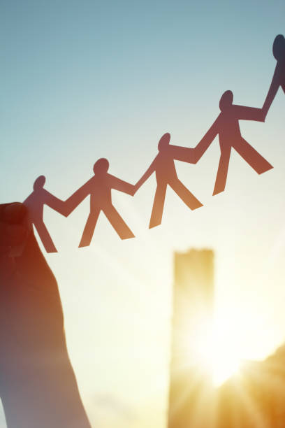 istock Hands Holding Paper Human Chain in the Sky Against Sunlight and Blue Sky 1222692430