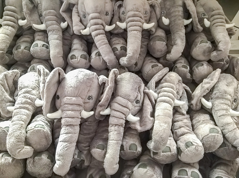many elephant dolls hang on the wall for sale in store.