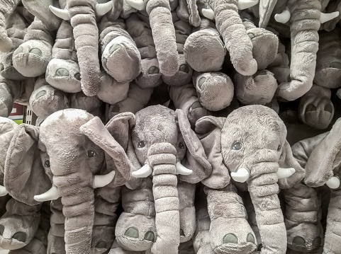 many elephant dolls hang on the wall for sale in store.