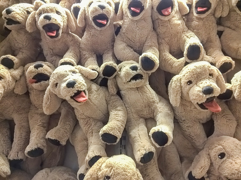 many dog dolls hang on the wall for sale in store.
