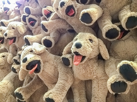 many dog dolls hang on the wall for sale in store.