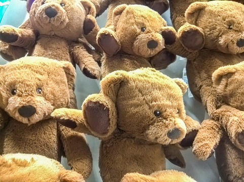 many bear dolls hang on the wall for sale in store.